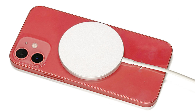 MagSafe充電器をiPhone 12 mini背面にセットしてQi充電している様子。MagSafe充電器は、磁力により端末背面の最適な位置に自動吸着され、端末側と充電器側のコイルが正しい位置関係となり、最適な状態で充電される。