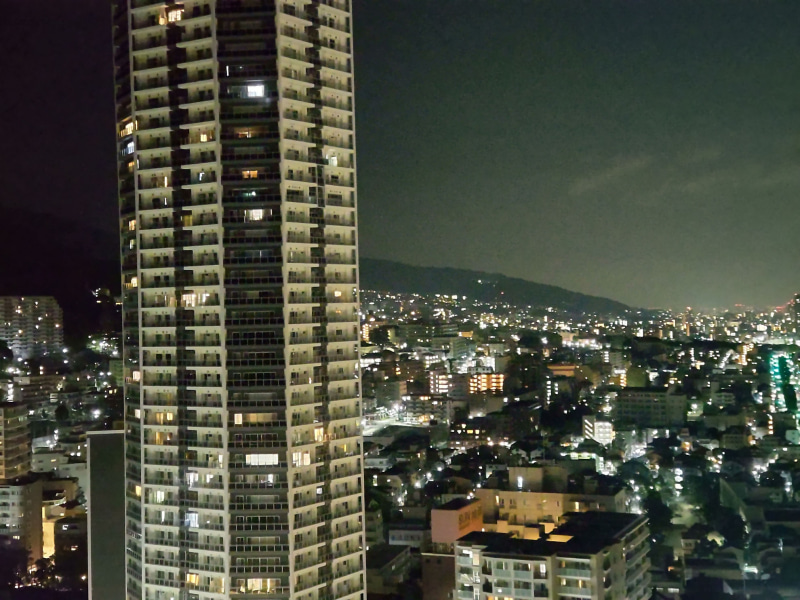 「AQUOS sense5G SH-53A」の「ナイトモード」で、夜景を望遠カメラで撮影。広角や標準に比べ、やや粗さが目に付く。左のビルも少し歪んで見える