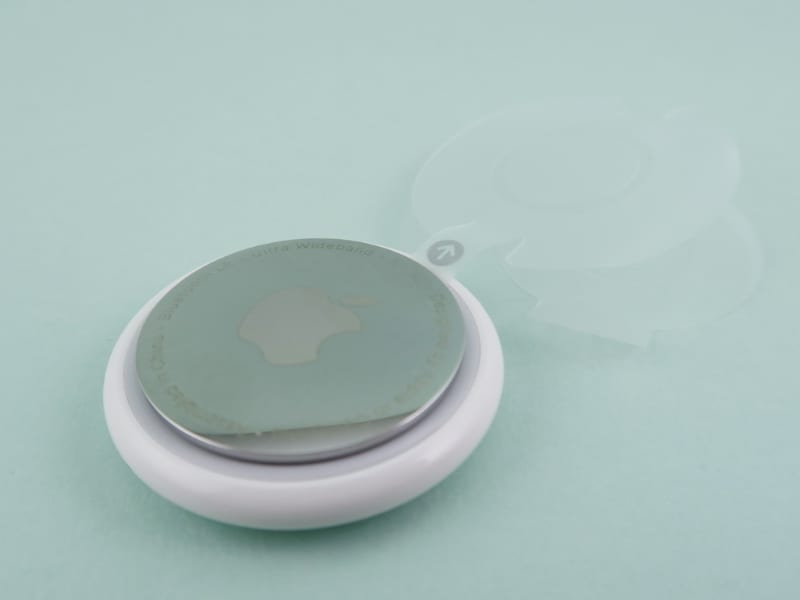 保護フィルムを剥がすと、矢印の部分が「AirTag」の内部につながっている。この部分を引き抜くと、ボタン電池が通電し、「AirTag」が動作する