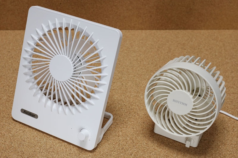 左はAmazonにて2980円で買ったavolkerブランド<a href="https://www.amazon.co.jp/dp/B07SBV1QJK/" class="strong bn" target="_blank">「USB扇風機」</a>。USB充電式で、風量の無段階調節ができたり、スマートフォンに給電できたりする。サイズは15×18×7cmといったところ。リズムのSilky Wind Sと比べるとかなり大きいが、風量はSilky Wind Sの方が多かったりする