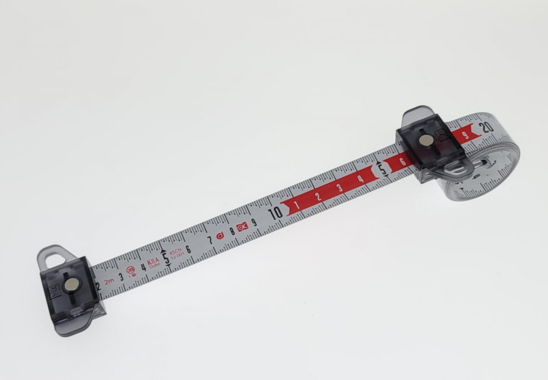 先端のスライダーを引っ張ってスパイラルメジャーを引き出して測定する