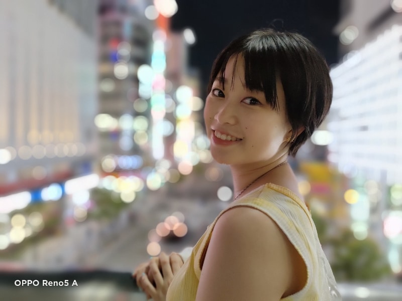 夜の街並みをバックに「ネオンポートレート」で撮影。人物にピントが合い、背景のライトが球状に表示された