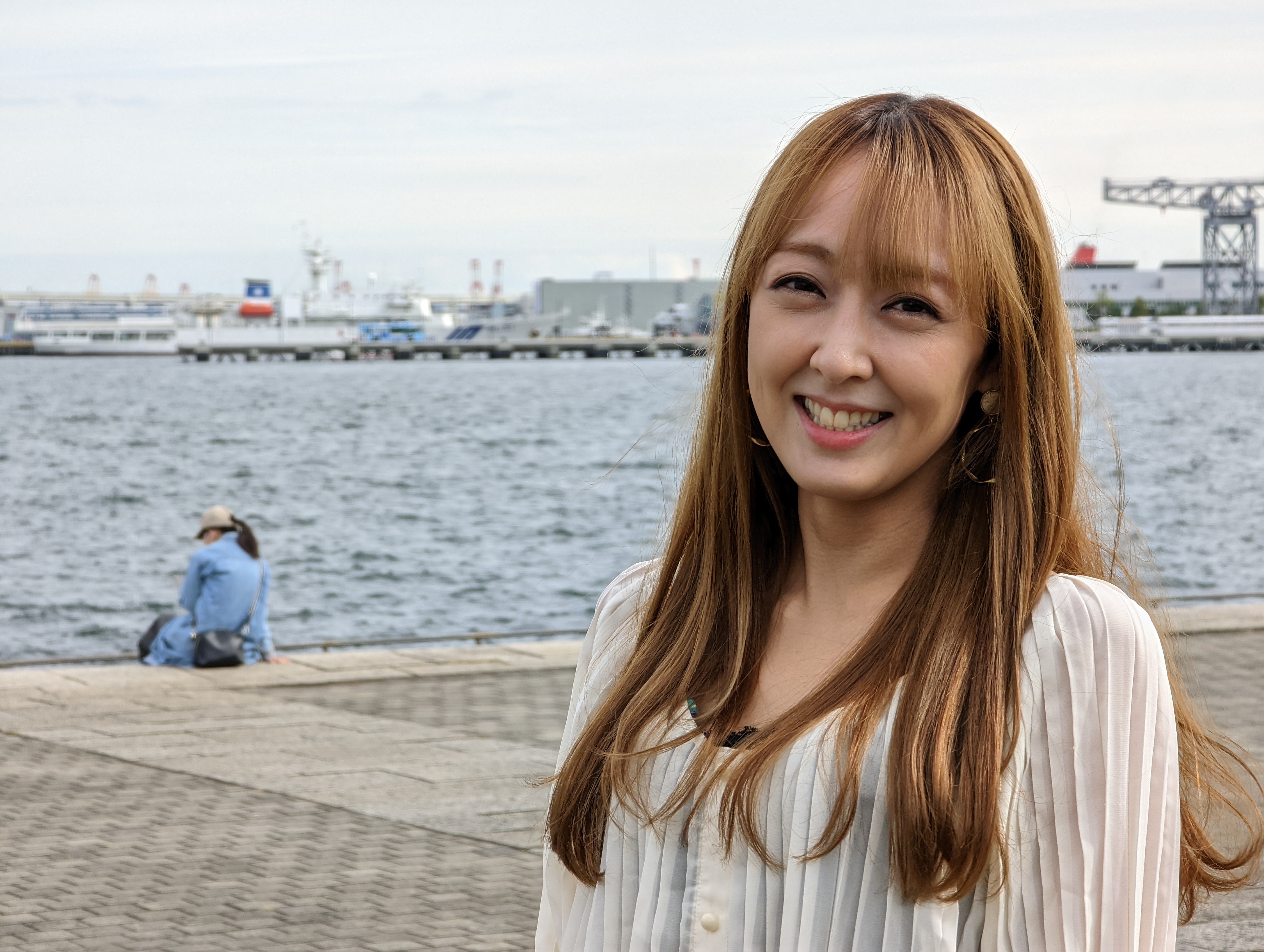 港をバックに記念写真を撮った。しかし画面左に見知らぬ人が……（モデル：佐藤ようか）