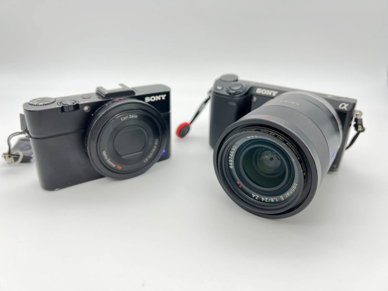 筆者のデジカメ、DSC-RX100M2（左）とNEX-5R（右）。NEX-5Rにつけてるレンズはそこそこ良いレンズだ（本体より高いぞ）