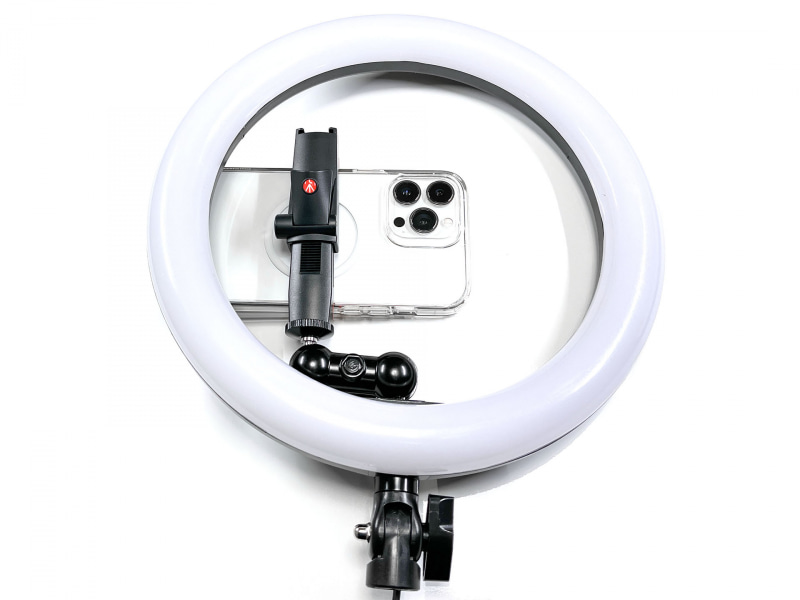 市販のLEDリングライト（10インチ）に、アームやホルダーを追加し、iPhoneをセットできるようにしている。撮影時はこのまま手に持って被写体に向けたり、別途三脚などを使って固定（自立）させて撮影している。