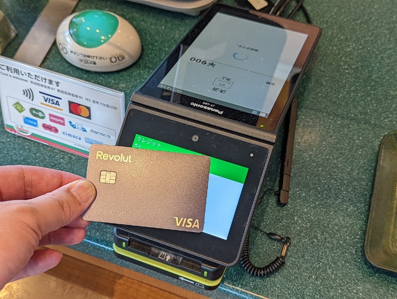 ラベンダー色のメタルカードでVisaのタッチ決済を行う