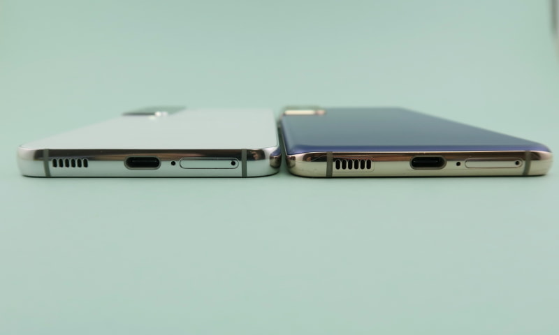 「Galaxy S22」（左）と「Galaxy S21 5G」を並べ、下部から見ると、背面のラウンドがなくなり、フラット仕上げになっていることがわかる