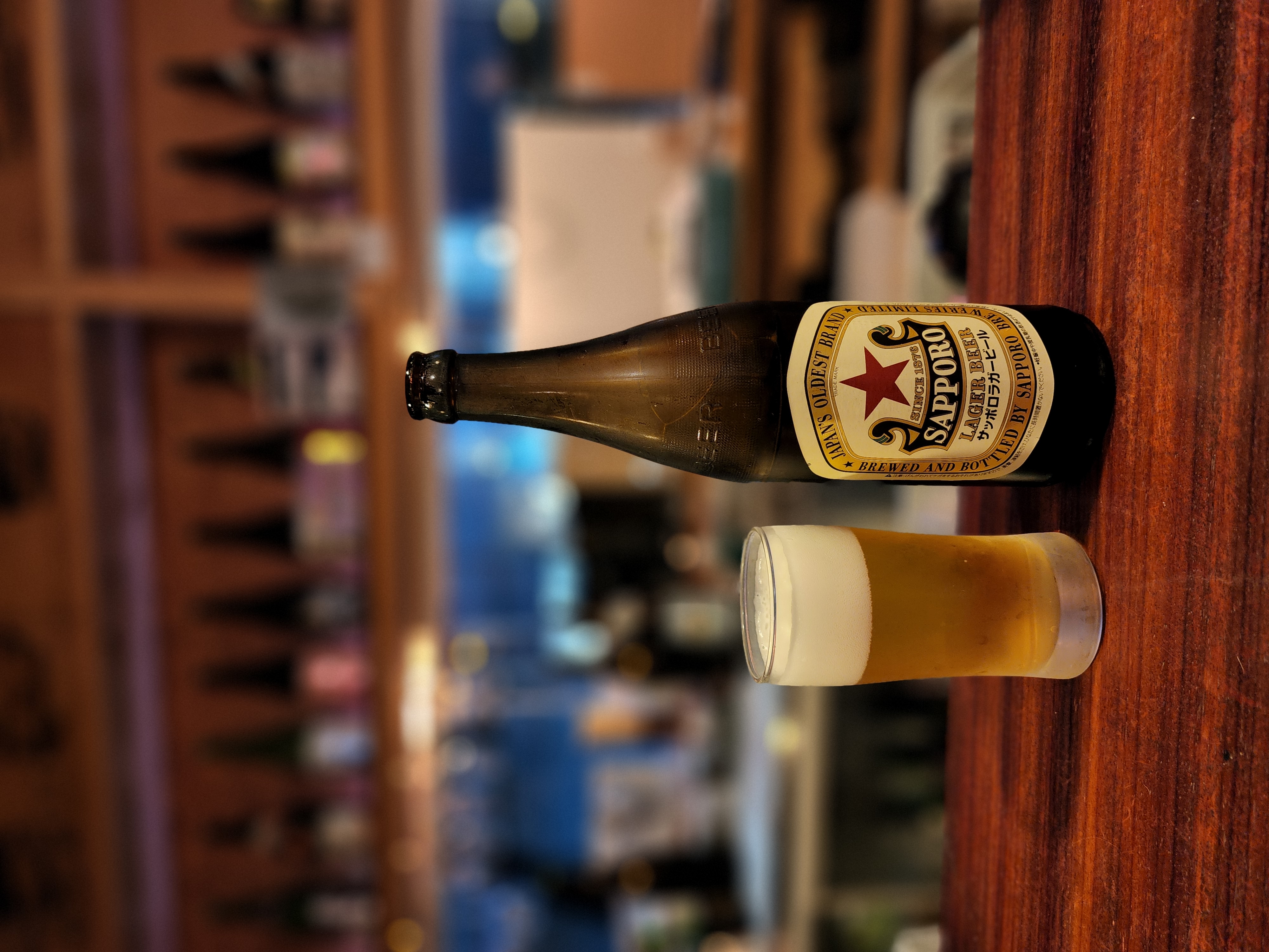 最近よく飲みに行く小田急線生田駅近くの立ち飲み屋「いちびり」。カウンターに大好きな「赤星」を置いてポートレートモードを試させてもらった。焦点距離的にややボケすぎ感があるが、しっかりと境界判定していて瓶ビールとグラスが浮かび上がった。