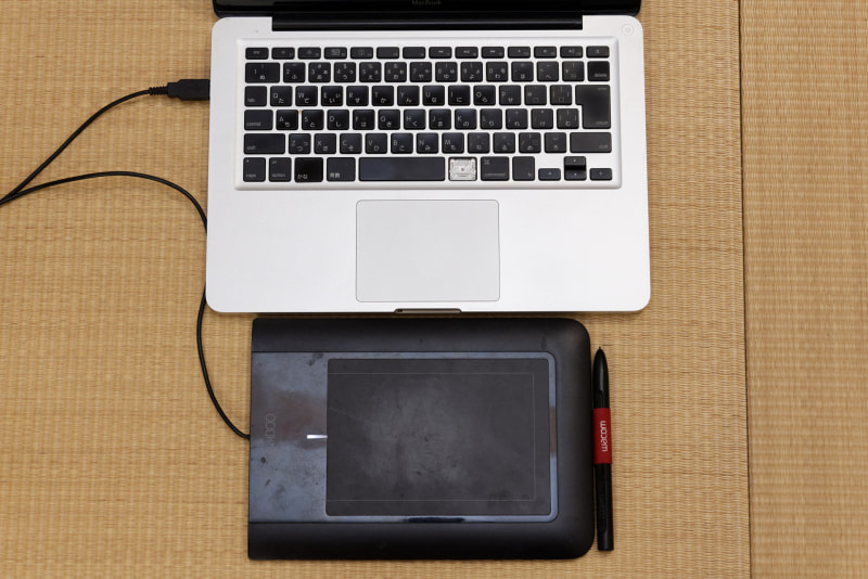 妻のMacBookと板タブ。一部のキートップはなくなり、押せないキーもある。SSD化で延命処置もしたが、もう十分働いたでしょう