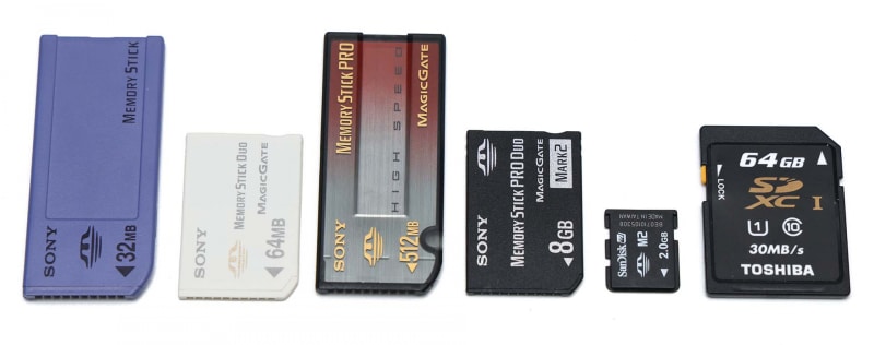 左から、メモリースティック、それを小型化したメモリースティックDuo、メモリースティックを大容量化したメモリースティックPRO、小型化と大容量化を同時に実現したメモリースティックPRO Duo、それを小型化したメモリースティックマイクロ（M2）など、ミョーにバリエーションが多いのであった。右端はSDメモリーカード。