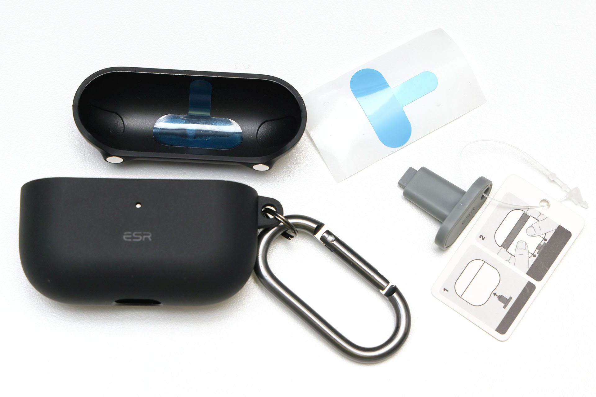 ケースは上下がセパレートのタイプで、ストラップホール付き。カラビナも付属する。ケース上部は両面テープでAirPods Proに貼るようにして使うが、予備の両面テープも付属していた。グレーのT字型のものは、ケース下部をAirPods Proから外すための治具。