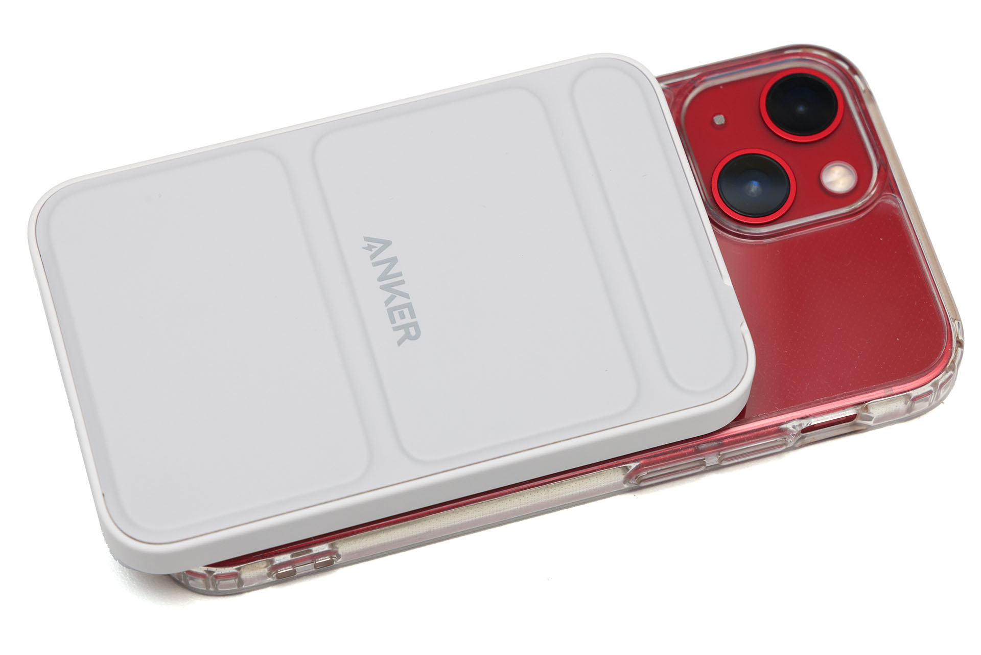 iPhone 13 mini（MagSafe対応ケース入り）に吸着した様子。しっかり吸着するが、バッテリー下端が端末からハミ出る。