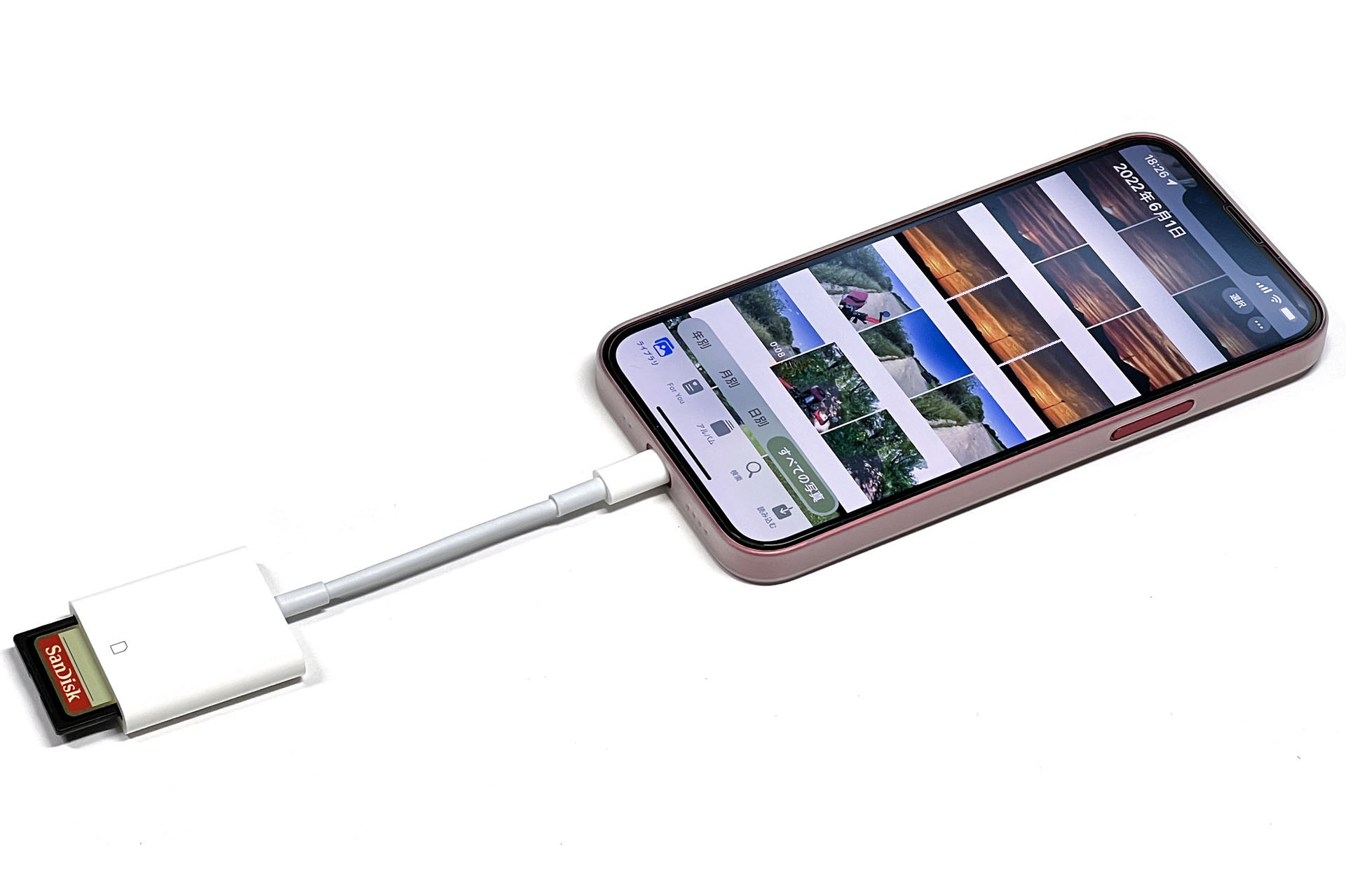 iPhoneでの画像読み込み手順。まずはカードリーダーを介してメモリーカードとiPhoneを接続する。この写真のカードリーダーはApple純正品（A1595）で、現在Appleストアで売られているものだが、非常によく似た旧製品（A1441）があり、中古品などで流通していることがあると思われる。旧製品（A1441）は、現行品（A1595）より転送速度が遅いので、購入時にはご注意を