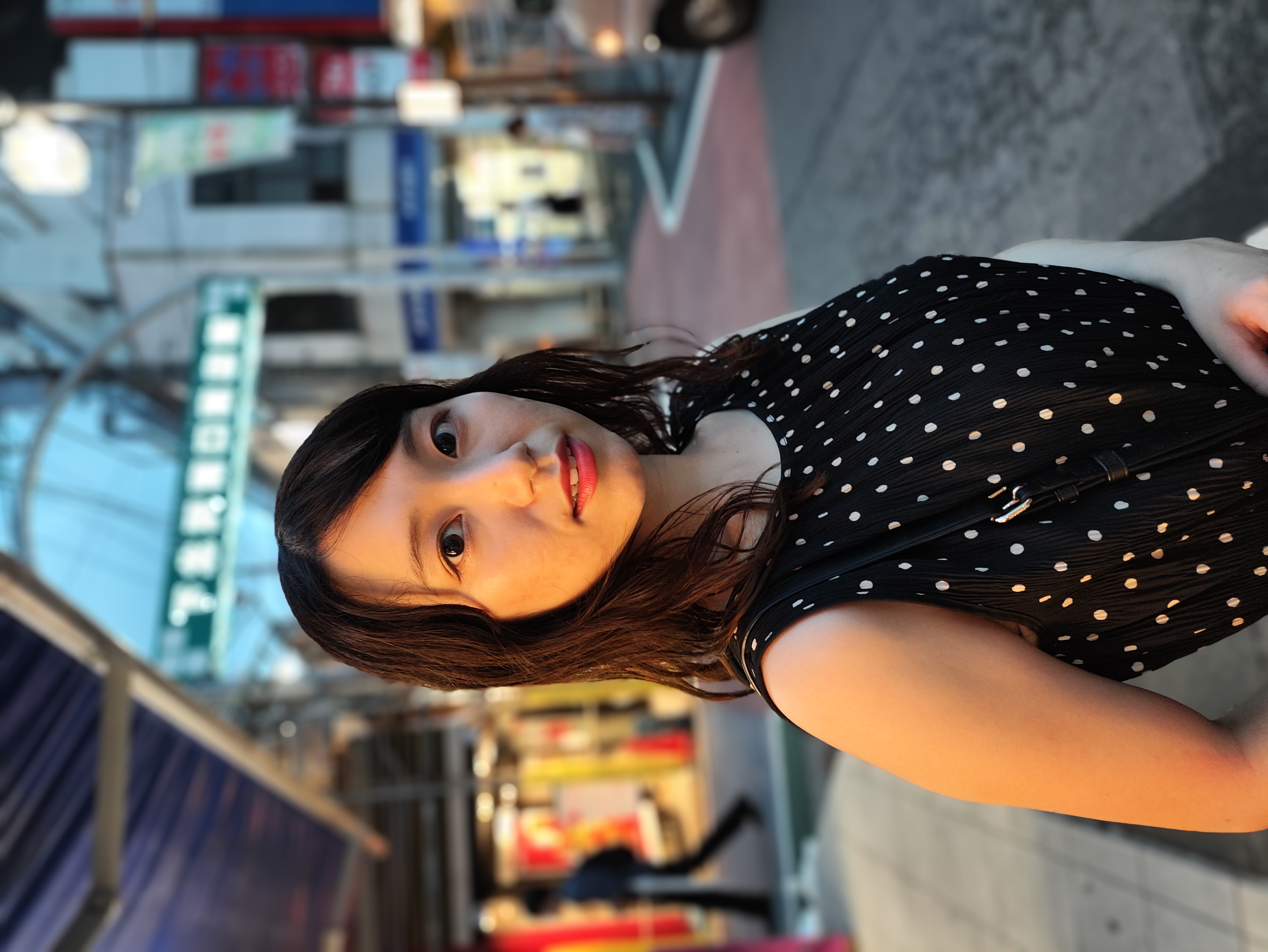 ポートレートで夕暮れ時に撮影。背景のボケで人物が際立っているが、背景の明かりの色合いがそれぞれ再現されている。モデル：井瀬遥（Twitter：@chibiharu___7、<a href="http://bonbon-famin.com/" class="strong bn" target="_blank">ボンボンファミン・プロダクション</a></a>）