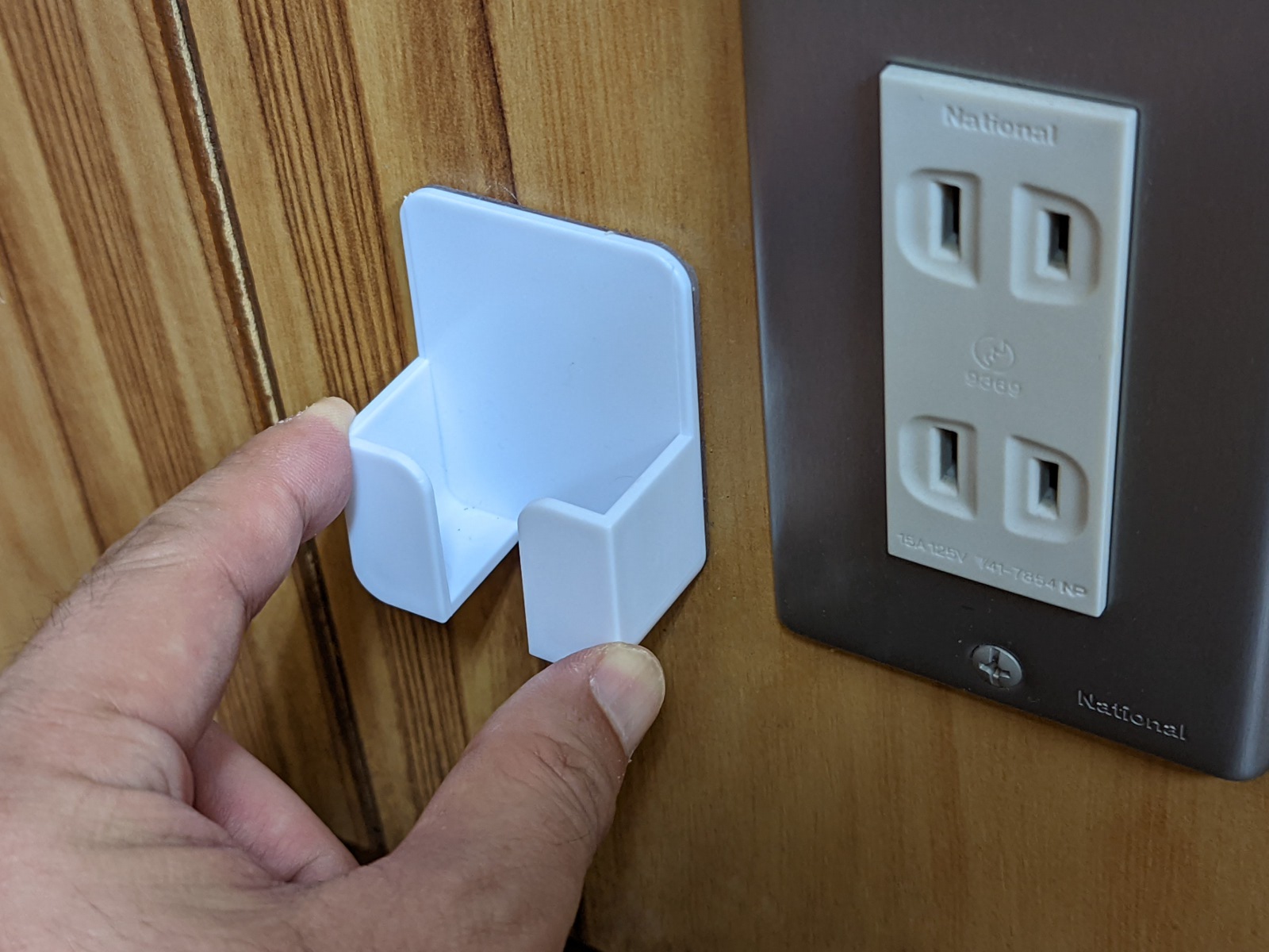 壁面コンセントの横に貼り付ける。粘着テープはかなり強力なので位置決めは慎重に