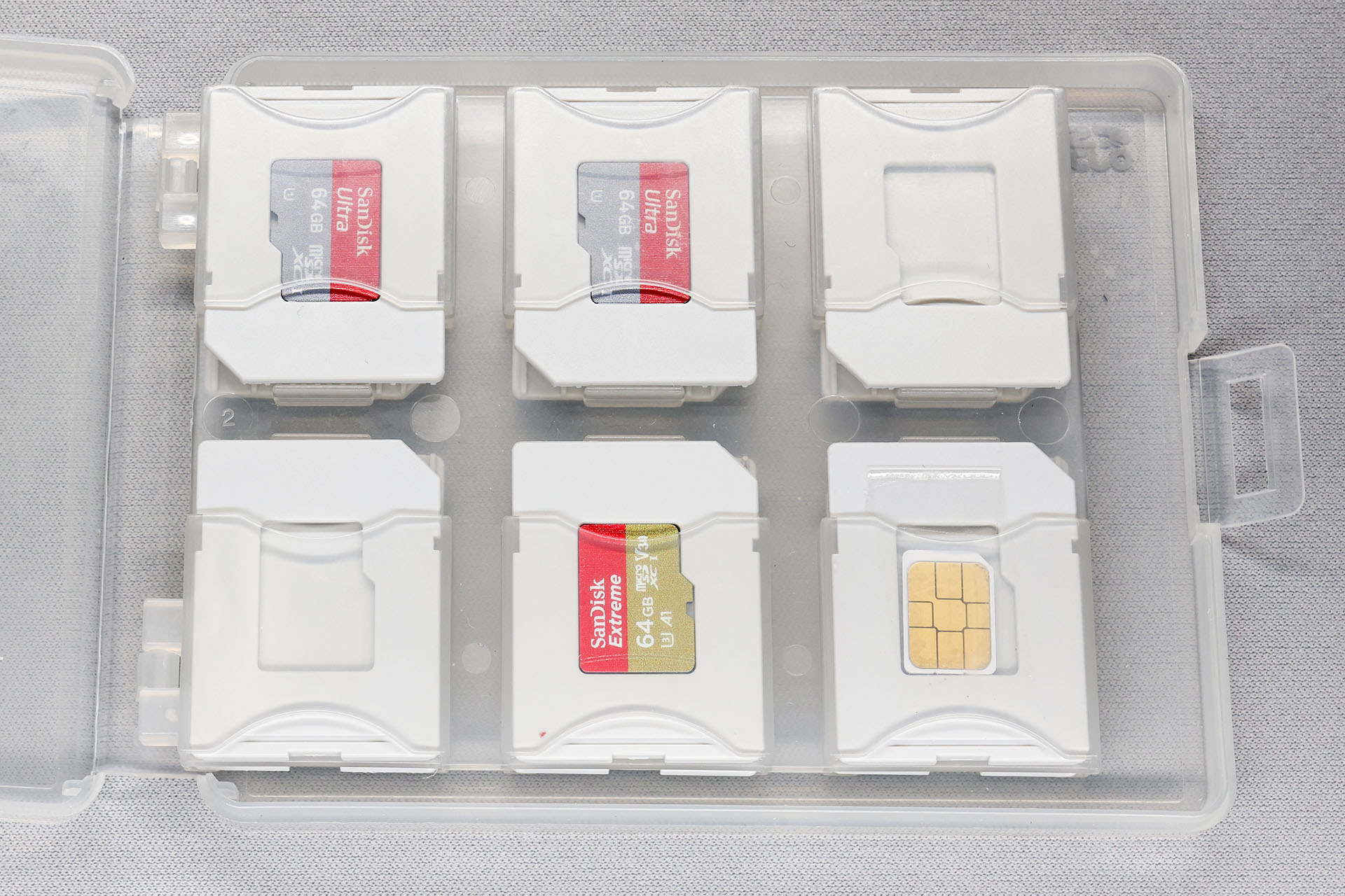 nanoSIMは、SIMカードアダプターにセットした状態で1枚入る。SD / microSD対応カードケース付属の（microSDカード→SDカードサイズ変換）トレイなどを使えば、3つのSDカード収納部にそれぞれnanoSIMを入れられる。たたし、トレイにはテープでフタを自作し、nanoSIM落下防止を施す必要がある。ともあれ、このケースにはnanoSIMが4枚入ることになる