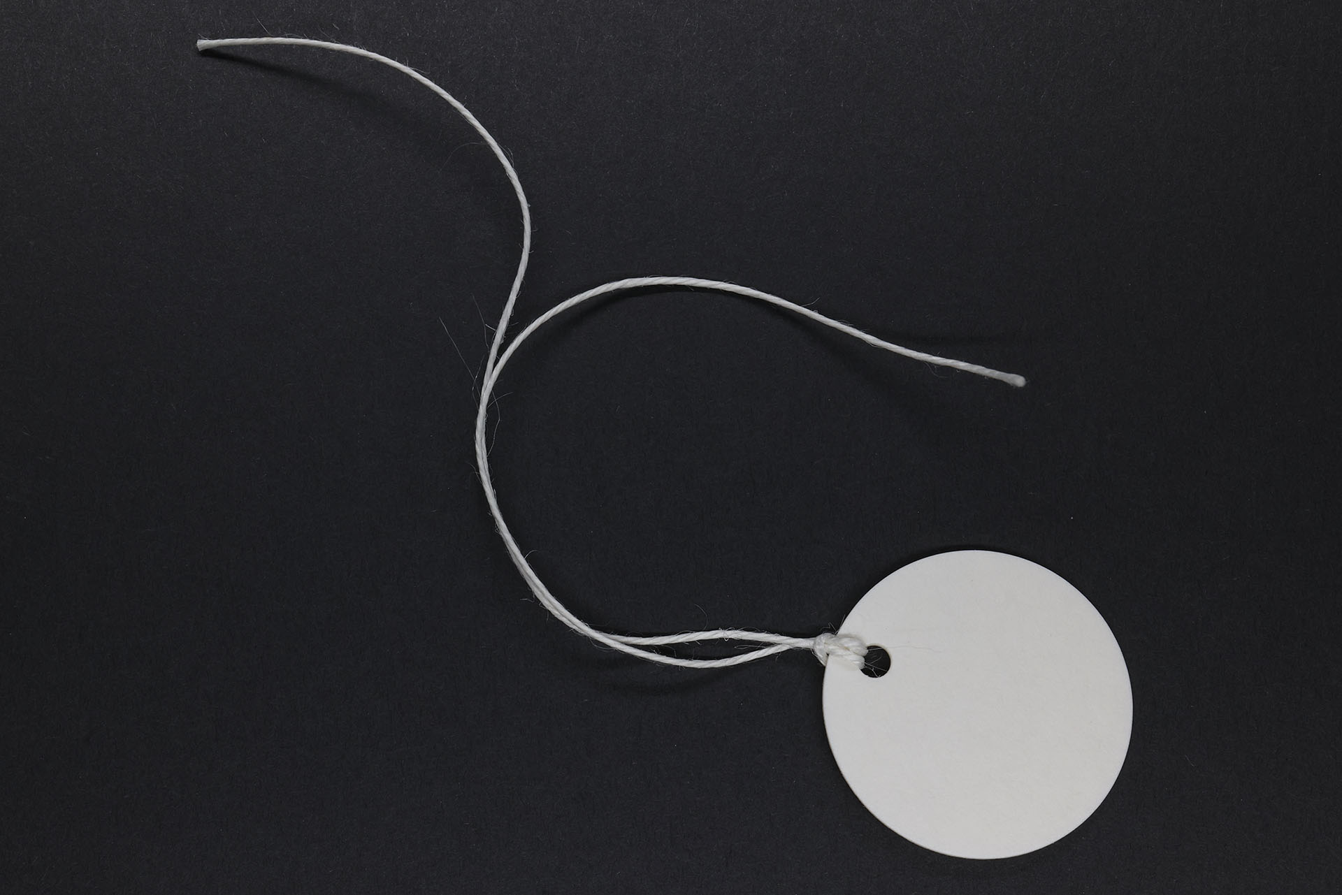 ファイバー紙製のプレートに紐が結んであるタグで、ケーブル分類をはじめ幅広く利用できる。プレート部は強く押し固められた紙などの繊維で、ある程度の防水性はある（製品による）ものの、屋外での使用には適さないように思う。ヒモは麻糸だと思われる。室内での使用なら十二分に耐久性があると感じられる。