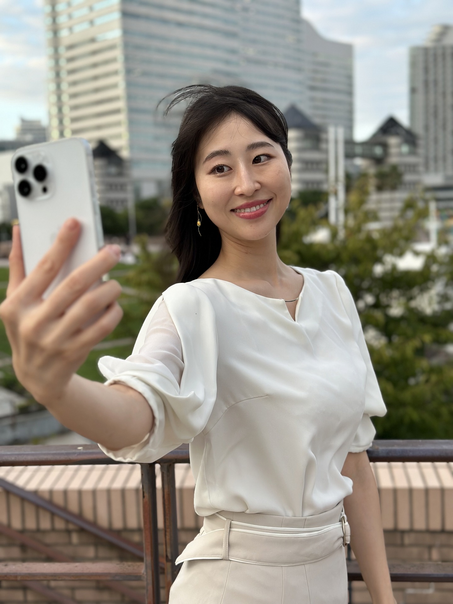 「iPhone 14 Pro Max」を手に持ってもらい、撮影。背景だけでなく、端末がわずかに前ボケになりながら、人物にはピントが合っている