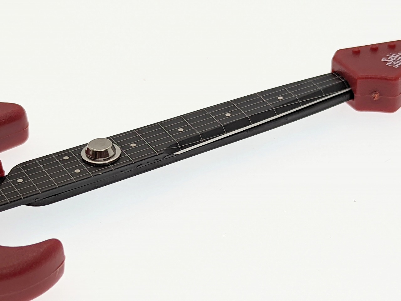 指板上のフレットやポジションマーク、6弦の描き込みが見事だ。弦は刃先のカーブに沿って曲がっているように見える。中央のネジがハサミとしてのまとまりを見せる