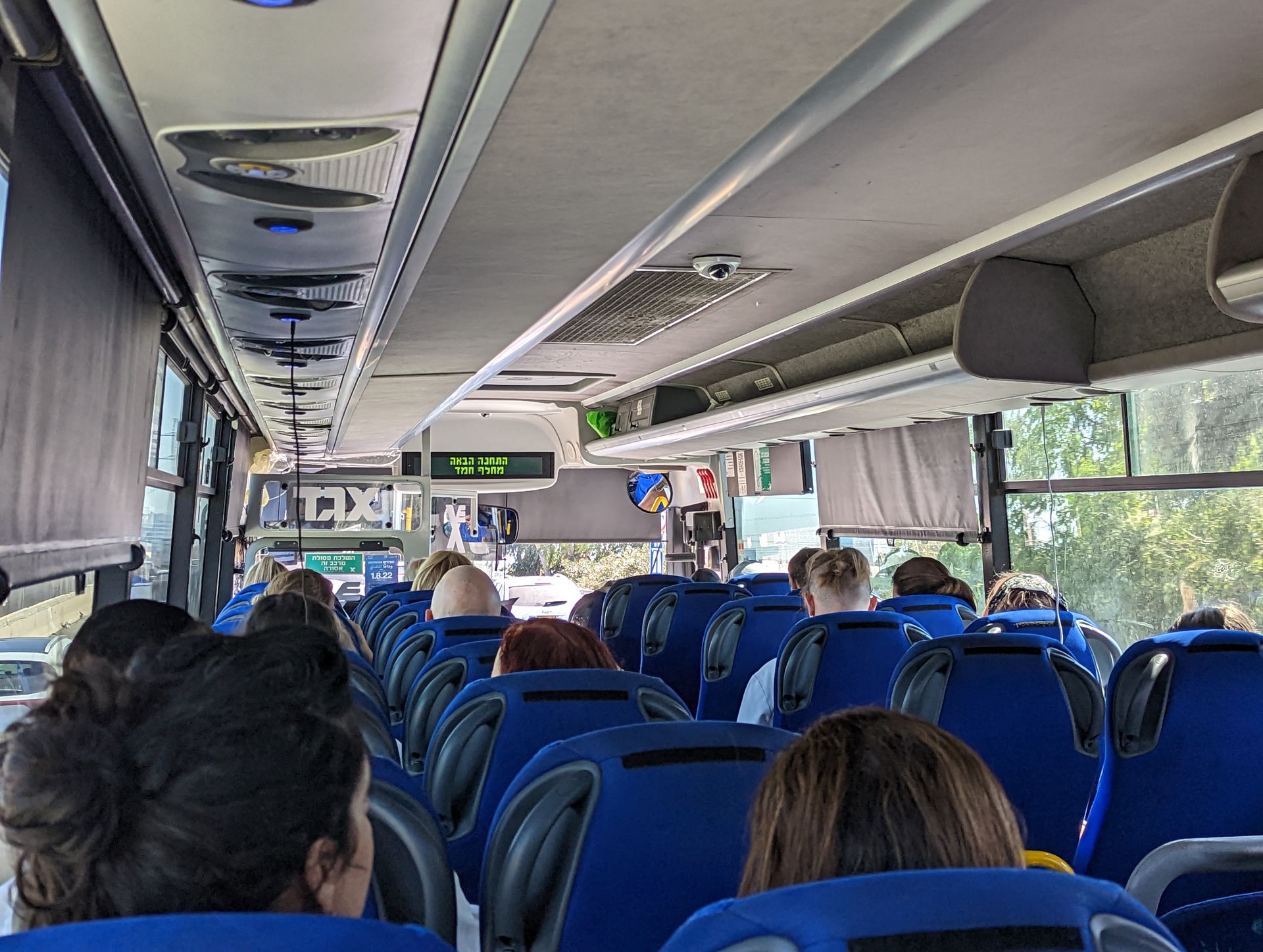 写真だと分かりにくいが、天井から座席に向かって何本もケーブルが垂れ下がっている。実は各席の頭上にUSBポートがあり、バス移動の30～40分間を使ってデバイスの充電が可能