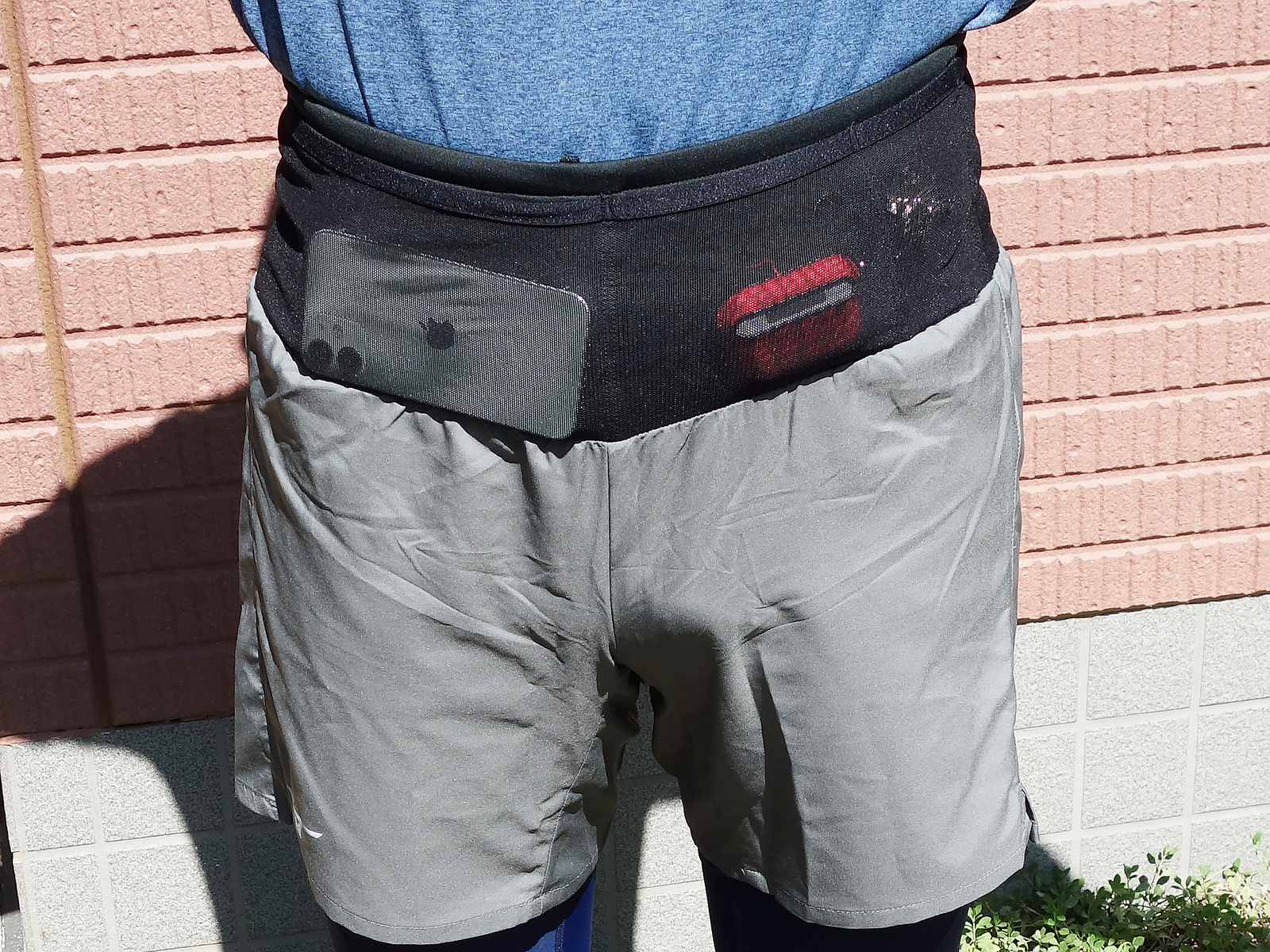 正面からモノを入れてみた様子。ケータイやイヤフォンのケース、カギなどが大小に分かれたポケットに収納可能です。