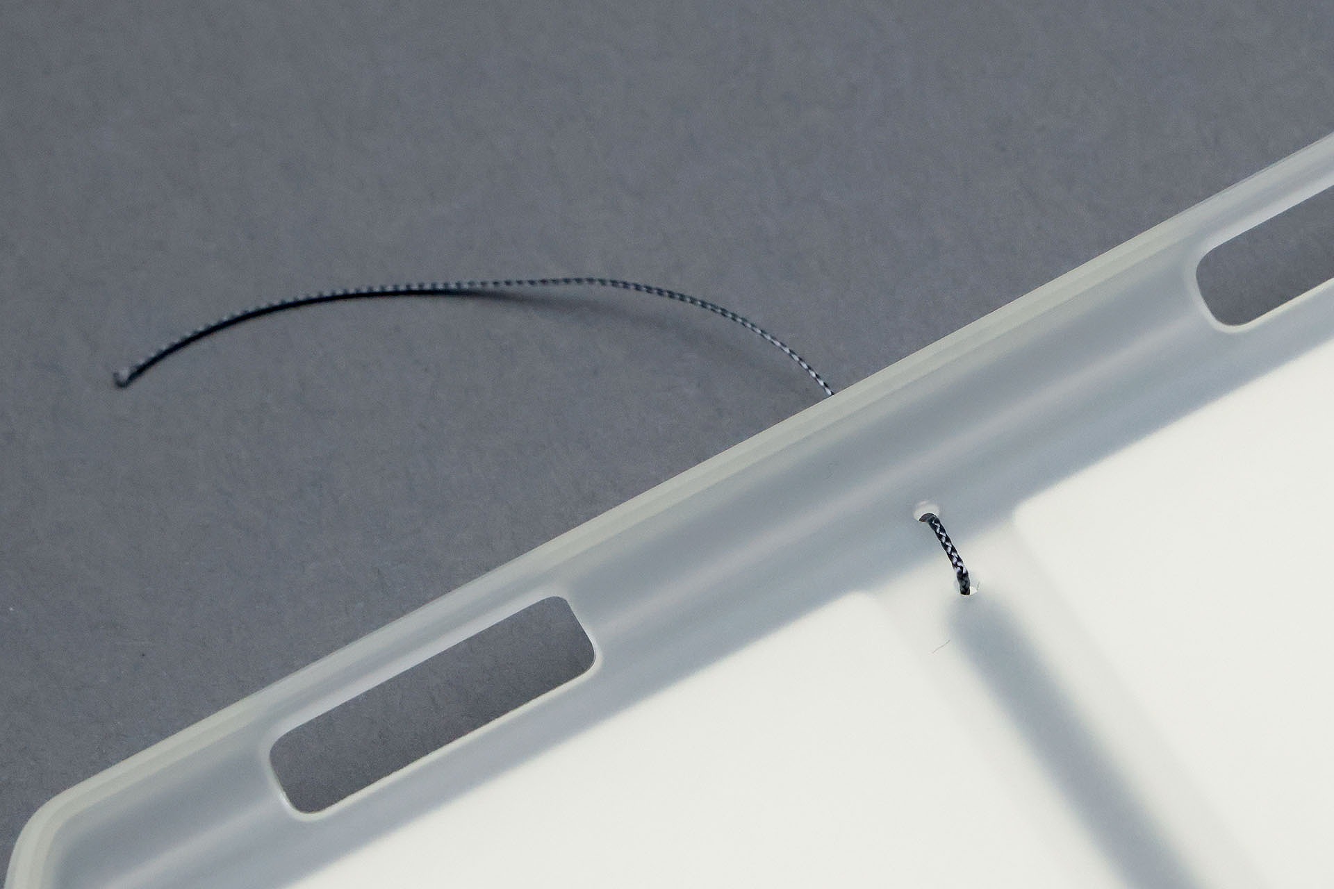 TPU製のタブレットケースに穴を開け、そこに紐を通して「カメラ三脚用タブレットデスク」に固定していく。これはタブレットが入る側で、タブレットと紐が接するが、紐が十分細いので問題ない。