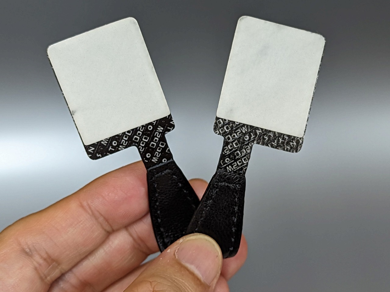 本体は短いストラップのような形状で、端に両面テープがついている。素材は牛革。なお現在市販されている製品は形状や素材、両面テープの仕様などが若干変更されているようだ