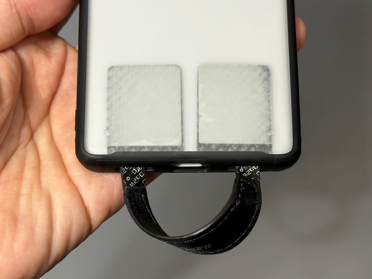 スマホケースのスピーカー穴から差し込み、両面テープでケースの裏側に貼り付ける。この例ではスマホケースが半透明なので見た目がよくないが、不透明なケースならば一体感があるだろう