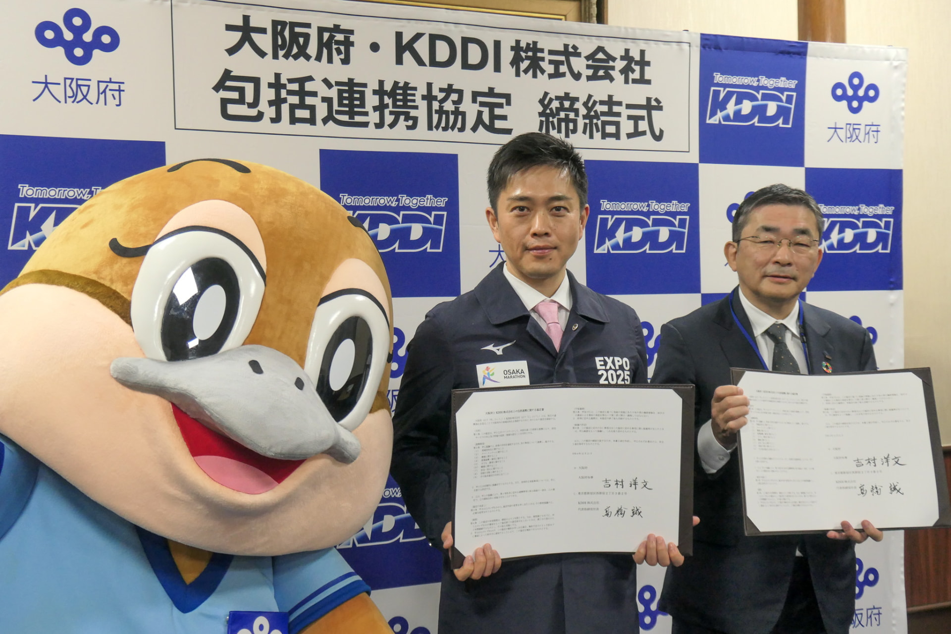 大阪府の吉村知事（中央）とKDDI髙橋社長（右）<br>左は大阪府のキャラクターである「もずやん」