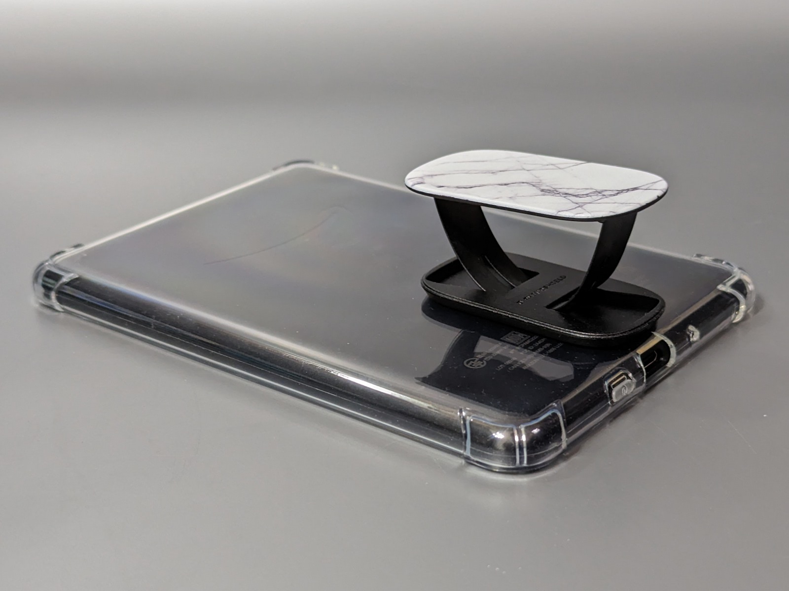 電子書籍端末（の保護ケース）に取り付けたところ。隙間に指を入れて保持する