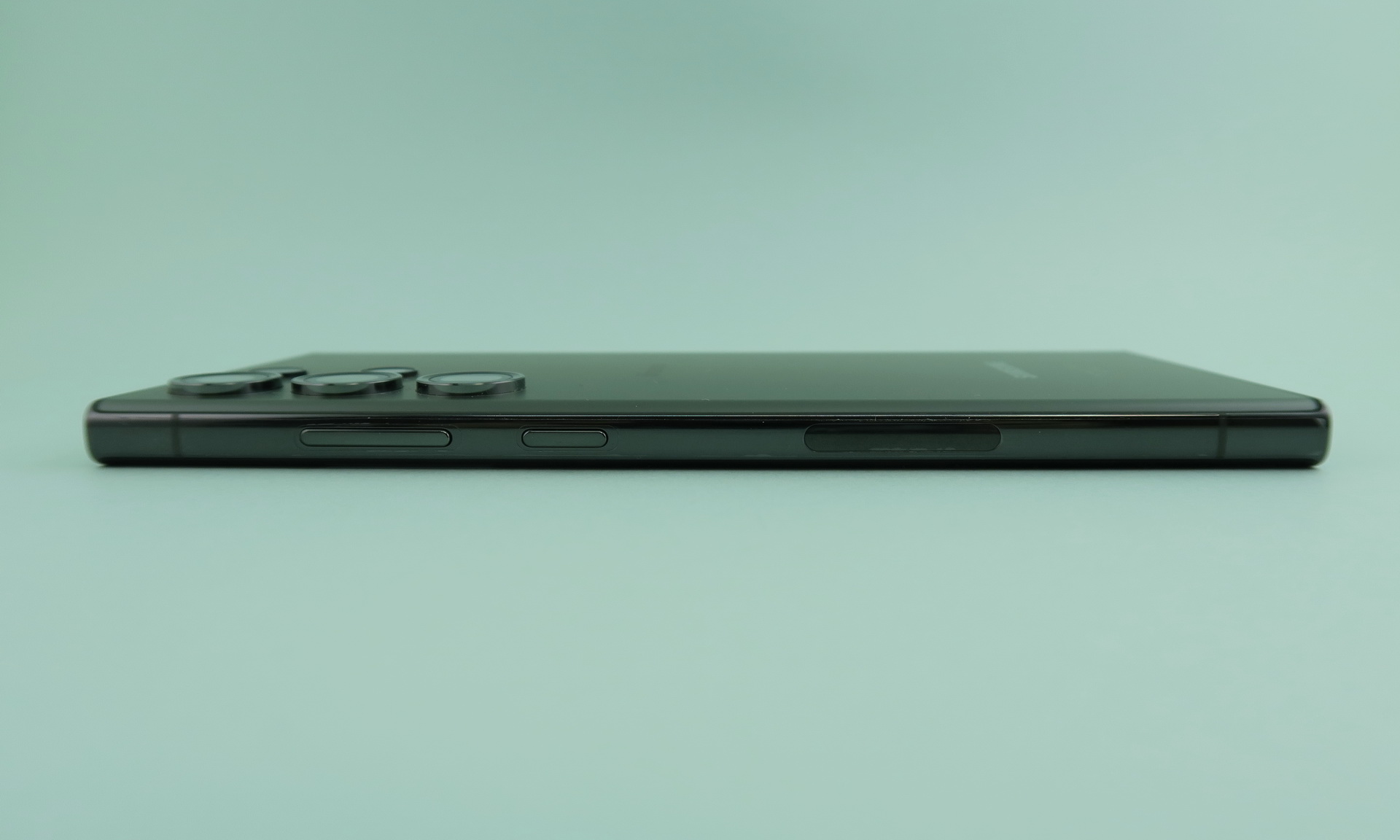 右側面には中央付近に電源キー、上部側（左側）にシーソー式音量キーが並ぶ。中央の下寄りの仕上げが異なる楕円パーツはおそらく内蔵アンテナをカバーする部分