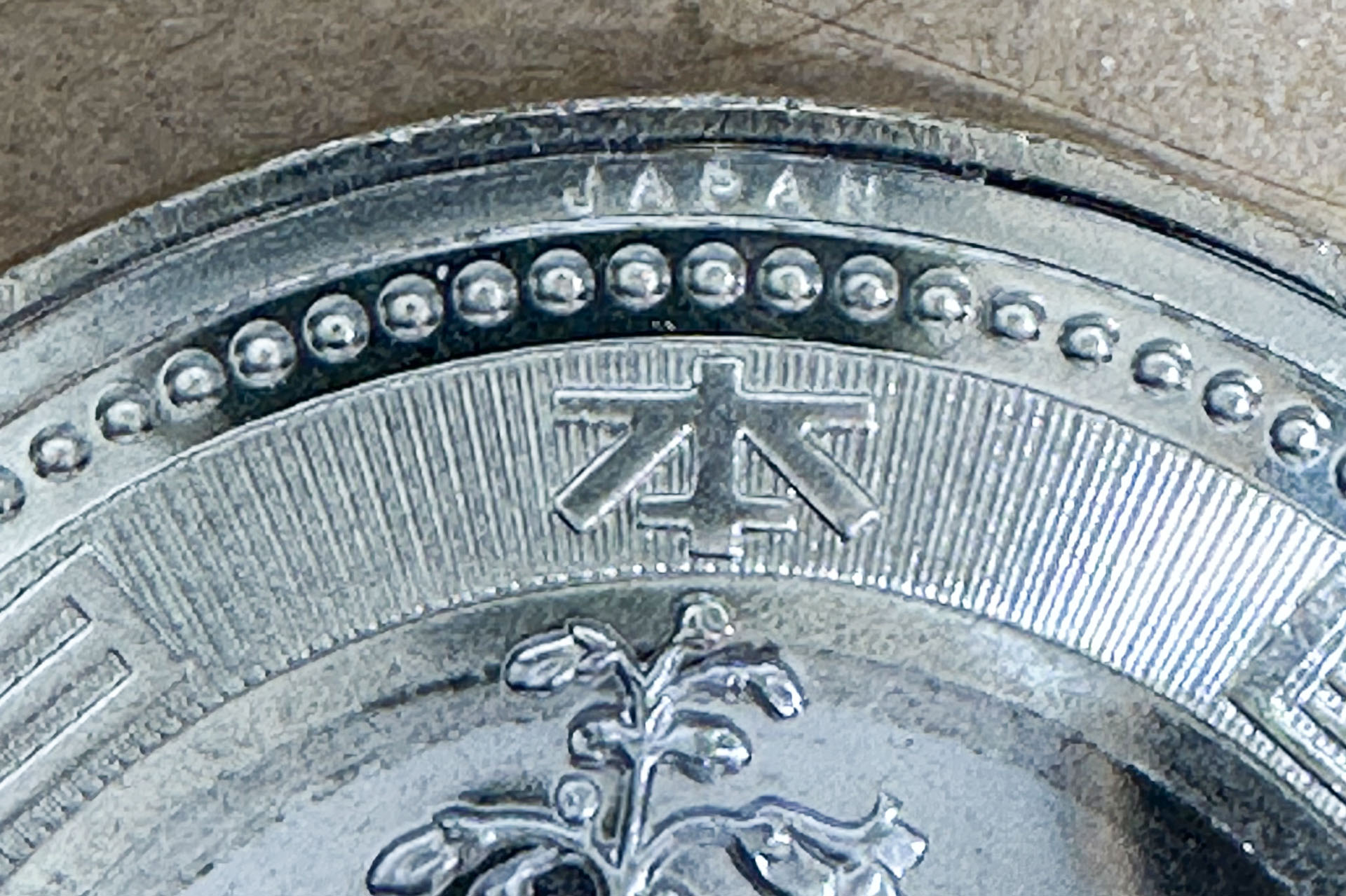新500円硬貨表面の上部にある「JAPAN」の刻印（微細文字）が写った。ややモヤッとした感じに見えるかもしれないが、iPhoneの画面上に表示させると、かなりクリアで精細に見える。