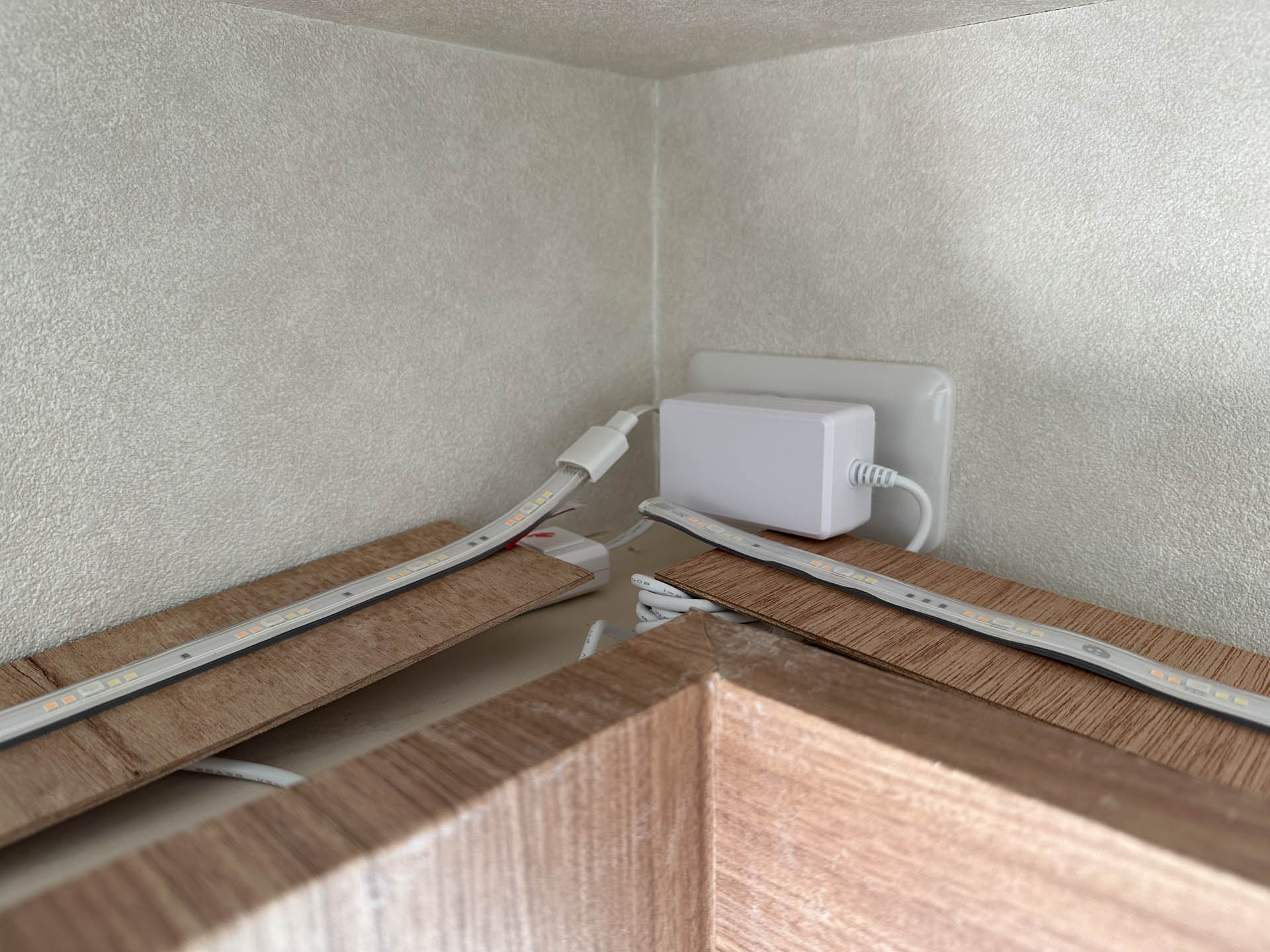 コーブ照明の中身。買った家具の梱包のベニヤ板を再利用し、そこにLEDテープを貼り付けるという不格好な素人工事だが、身長2.4mとかないと見えない位置なので問題なし