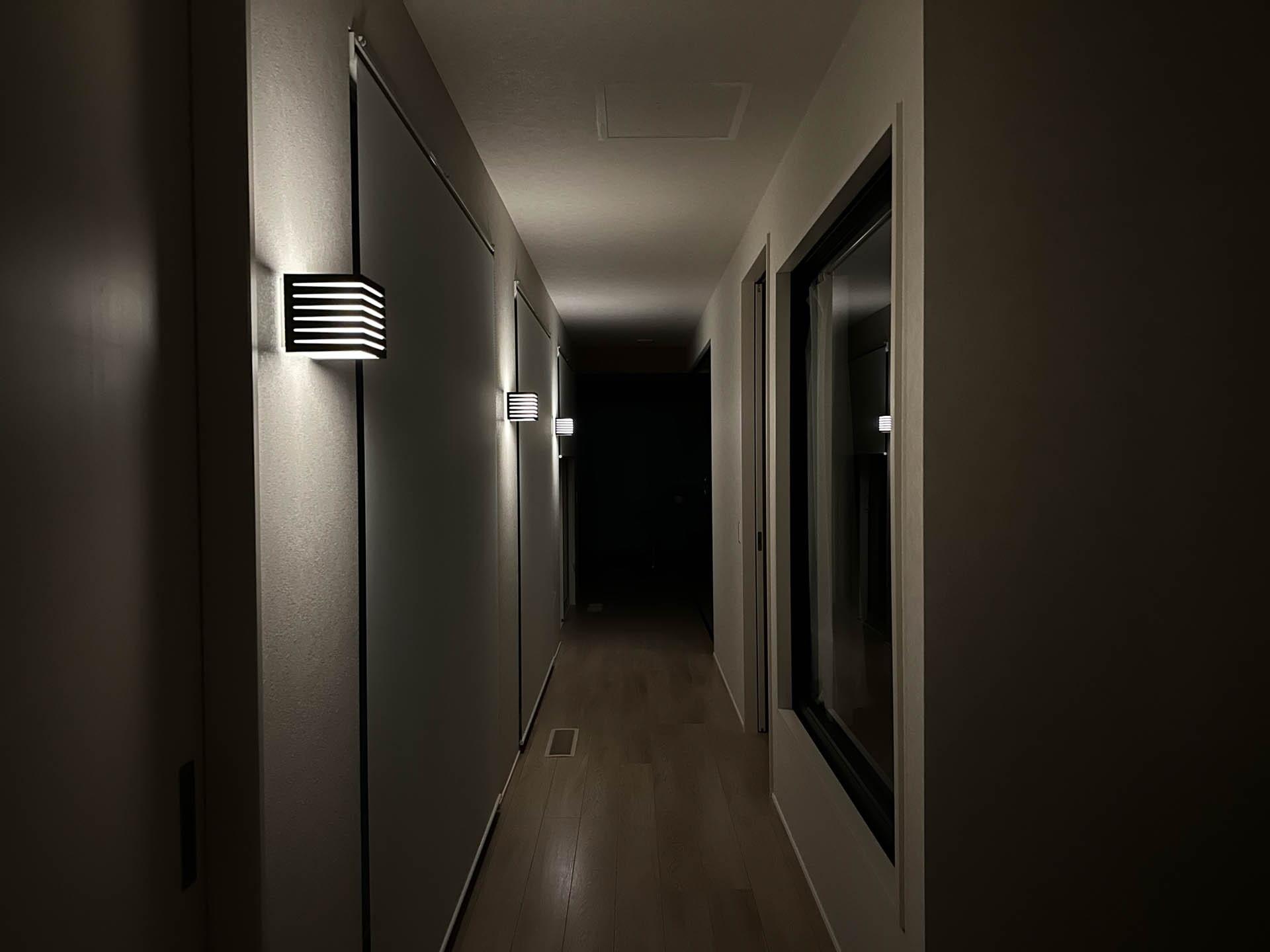 廊下の照明ブラケット。写真では白色だが実際には電球色にしている（変更できるけど）。あとあえて暗めにしている。ちなみに似た照明ブラケットでも汎用電球が使えないものもあるので注意