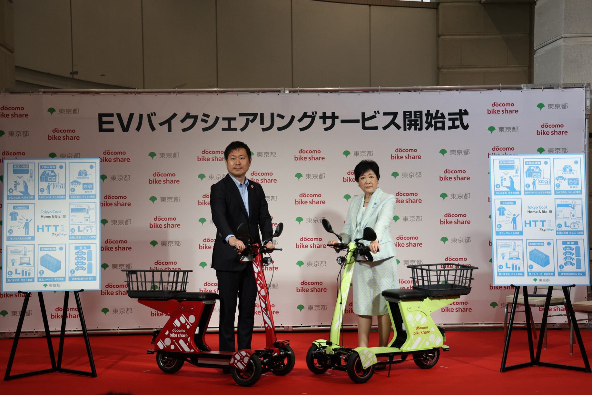 サービス開始式でEVバイクを手にするドコモ・バイクシェア 代表取締役社長の武岡 雅則氏（右）と東京都の小池 百合子都知事（左）。老若男女にEVバイクが浸透する日も遠くないはず