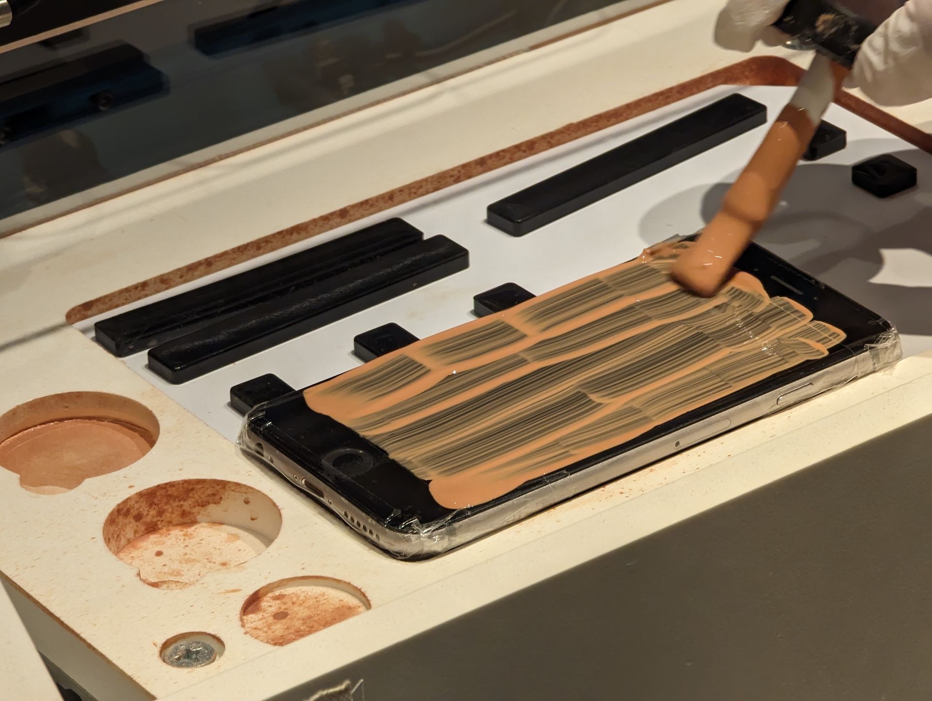 スマホに液状の研磨材を筆でたっぷり塗っていく