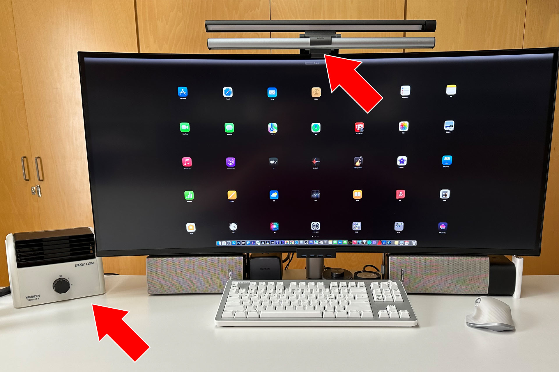 仕事場の机上。ディスプレイやキーボードがあり、その周辺にモニター掛け式ライトと卓上扇風機がある。これらが必需品となっている。