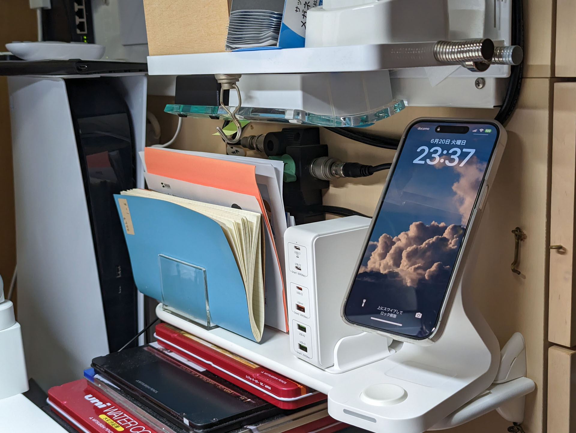 iPhoneをセットした様子。棚と棚の中間にあるので、高さ的にiPhoneの上部が上の棚に近い。問題なく使えるものの、「もう少し低い位置にiPhoneをセットできたらな〜」と、ときどき思うのであった。