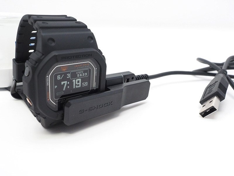 充電は、専用のUSB充電器を洗濯ばさみのように挟む。時計機能だけならソーラー充電だけでも稼働する