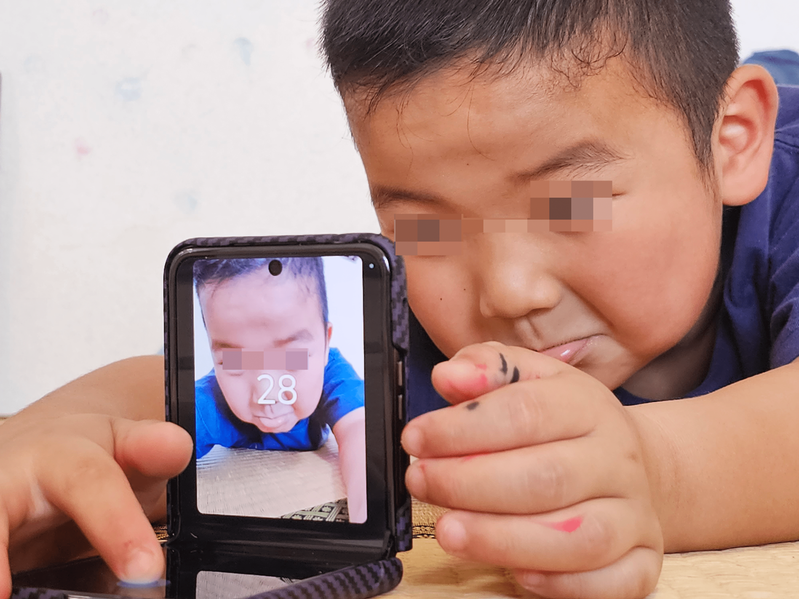 サブディスプレイて変顔を確認しながら自撮りを楽しむ子ども