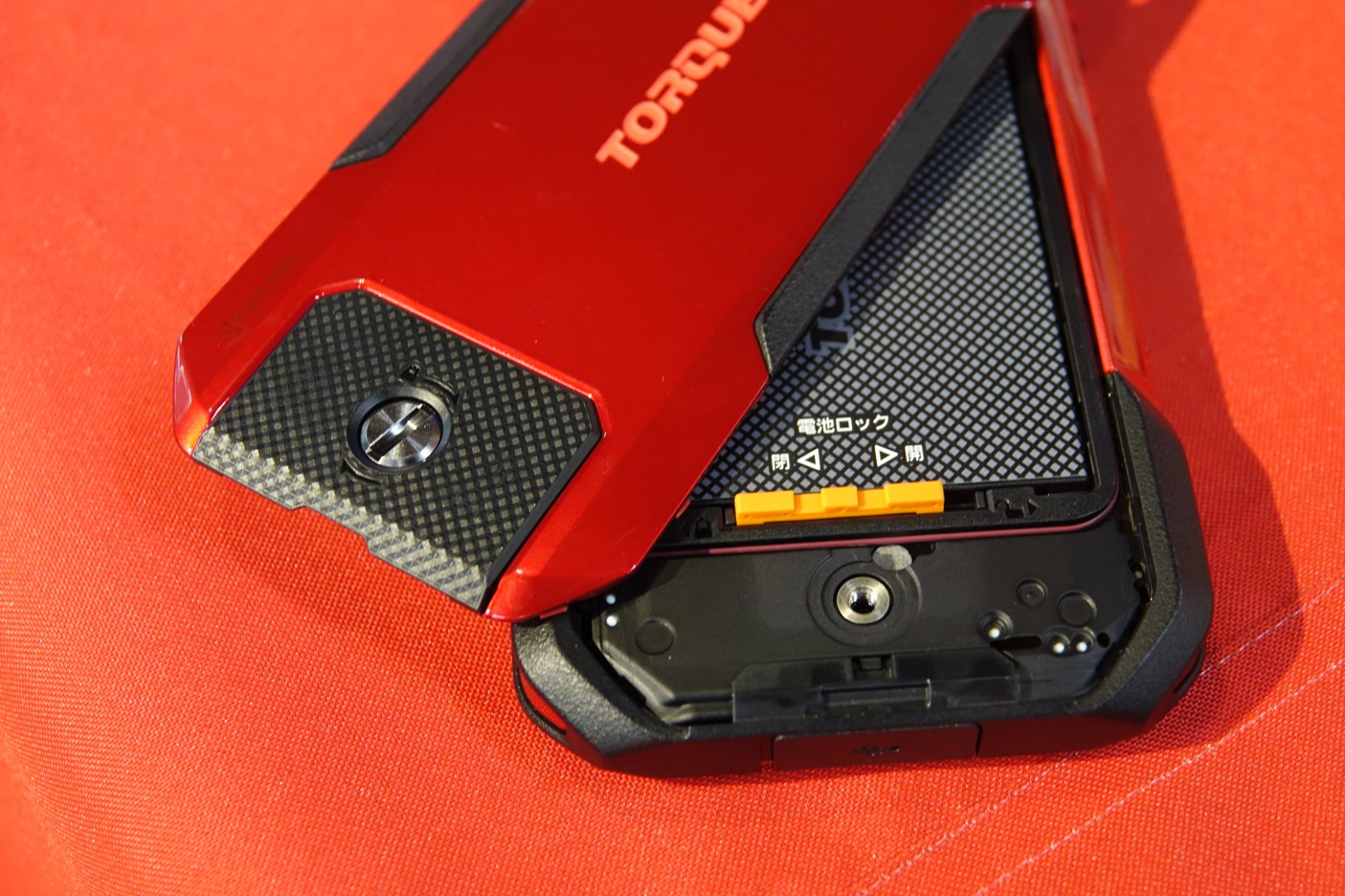 背面カバーは、下部のネジを回すことでロックが解除されるしくみ。先代モデルでは、90度回転させるだけでロック解除できたが、「小さい子供が誤って開けてしまうのを防ぐ」（担当者）などのため、今回はネジ式を採用している。ネジはコインなどを使って回せる