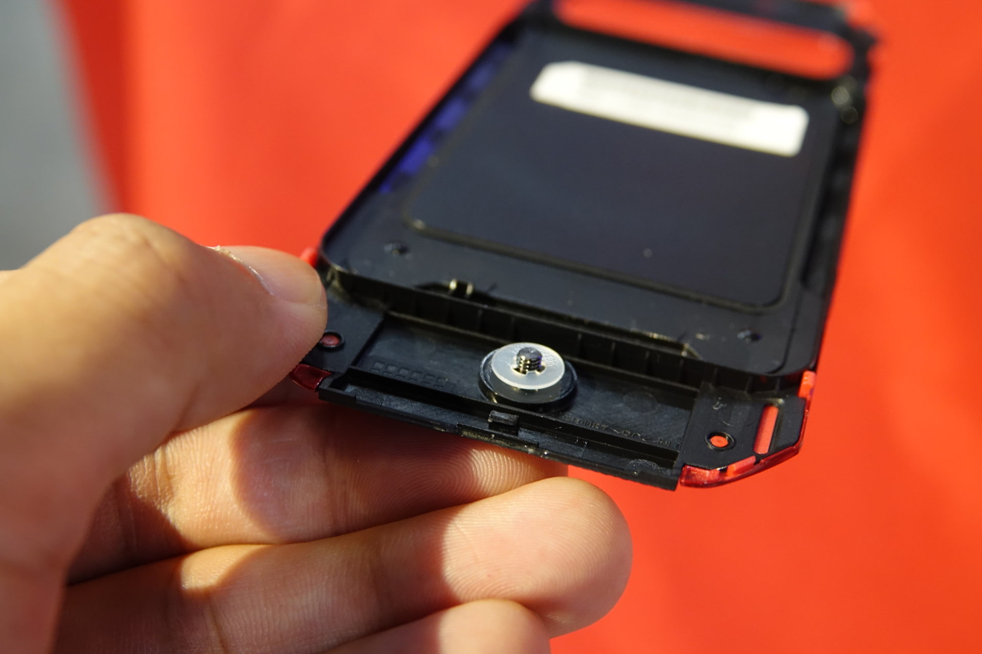 背面カバーは、下部のネジを回すことでロックが解除されるしくみ。先代モデルでは、90度回転させるだけでロック解除できたが、「小さい子供が誤って開けてしまうのを防ぐ」（担当者）などのため、今回はネジ式を採用している。ネジはコインなどを使って回せる