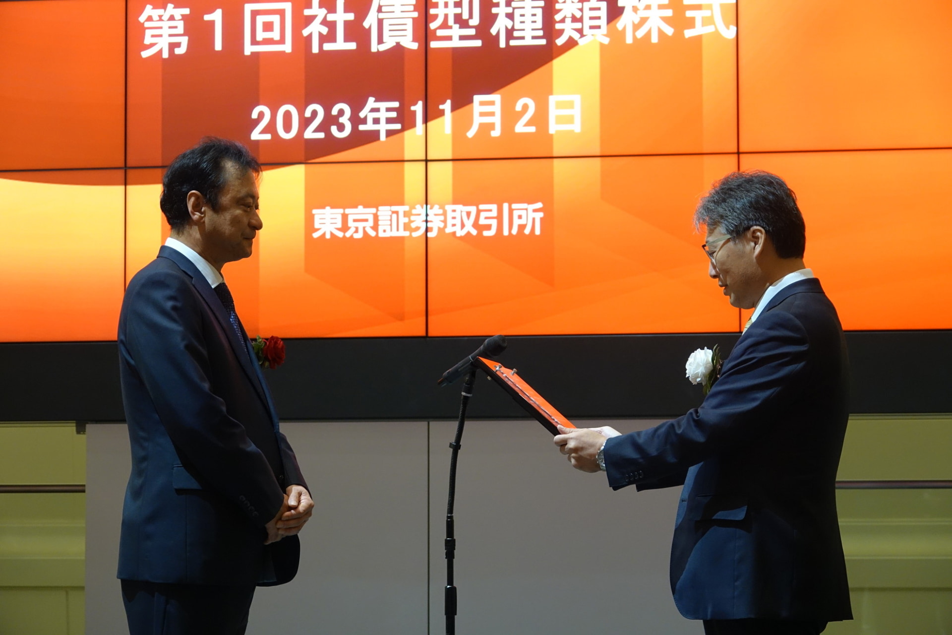 「上場通知書」を受け取る宮川氏（左）