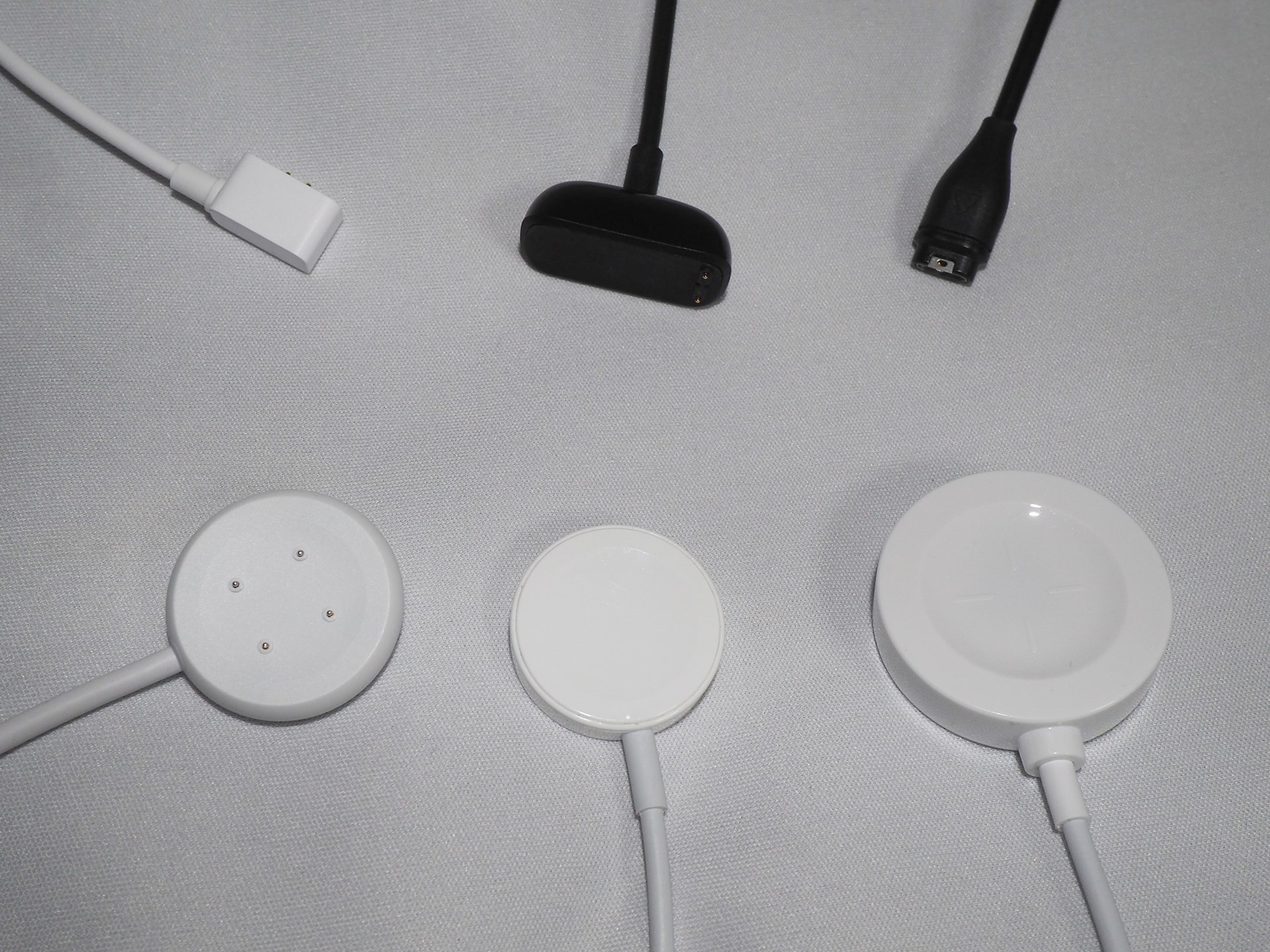 とりあえず近くにあったスマートウォッチとスマートバンドの充電器を並べてみたところ。全て異なるメーカー製のものだが、接点・無接点の違いや形状の違いなど、全く違う物が多いので使い回せない