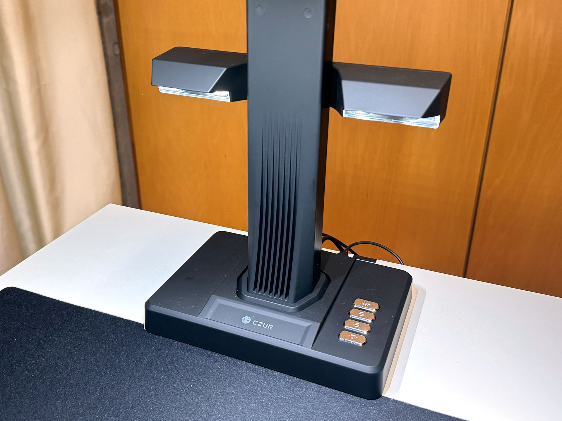 支柱中央付近にあるのは着脱式サイドライト。ヘッド部のライトだと表面が反射してしまうような原稿を照らすのに使う。サイドライトとヘッド部のライトを同時に使うこともできる。