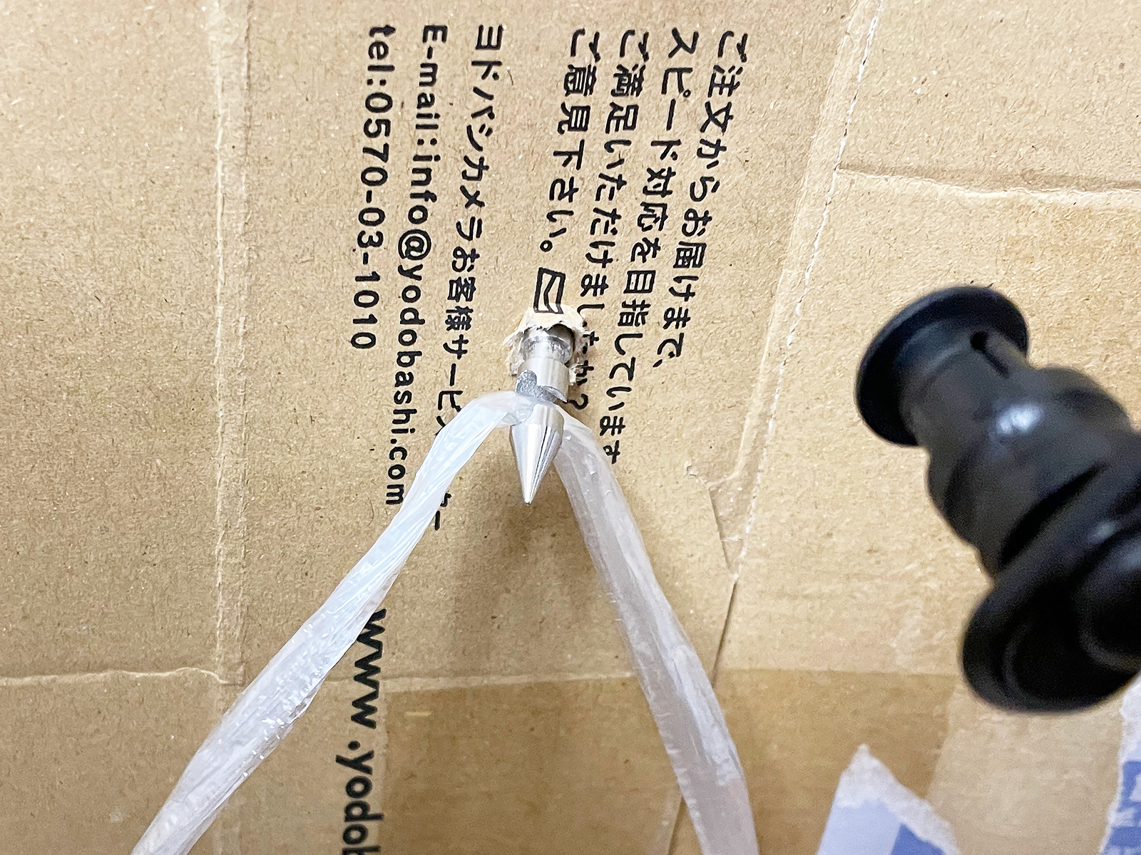 針の先にある「かえし」の部分にヒモをひっかけて、針を引き抜くとこのようにダンボールを貫いていた穴にヒモが通ります。