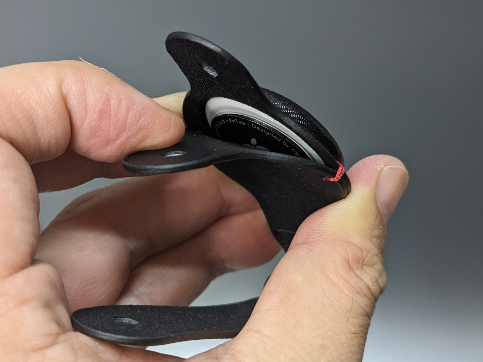 AirTagは二枚重ねになったボディの隙間から滑り込ませるようにして挿入する