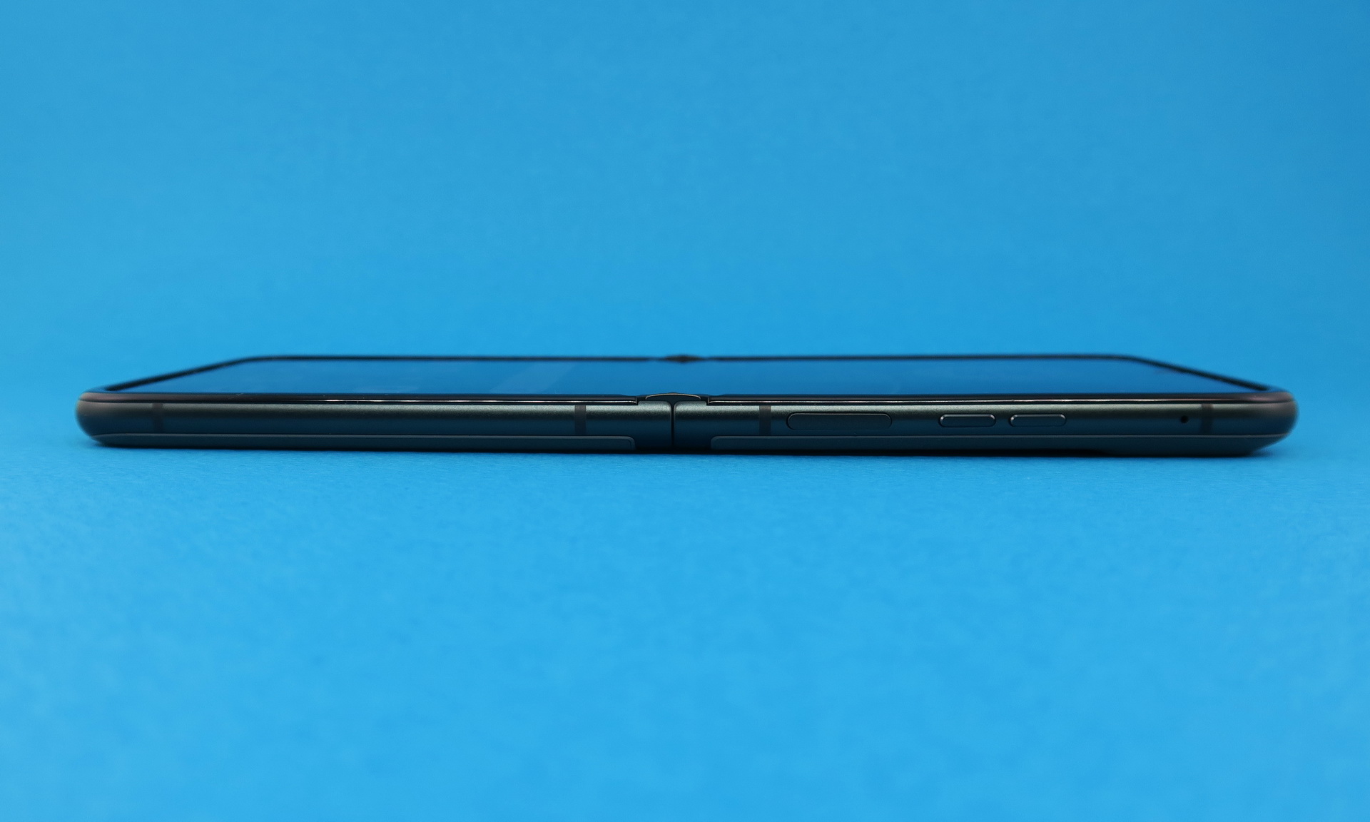 ボディカラーが暗いため、少しわかりにくいが、上側の筐体（右側）に分割式の音量キー、ヒンジに近い部分に指紋センサー内蔵の電源ボタンを備える