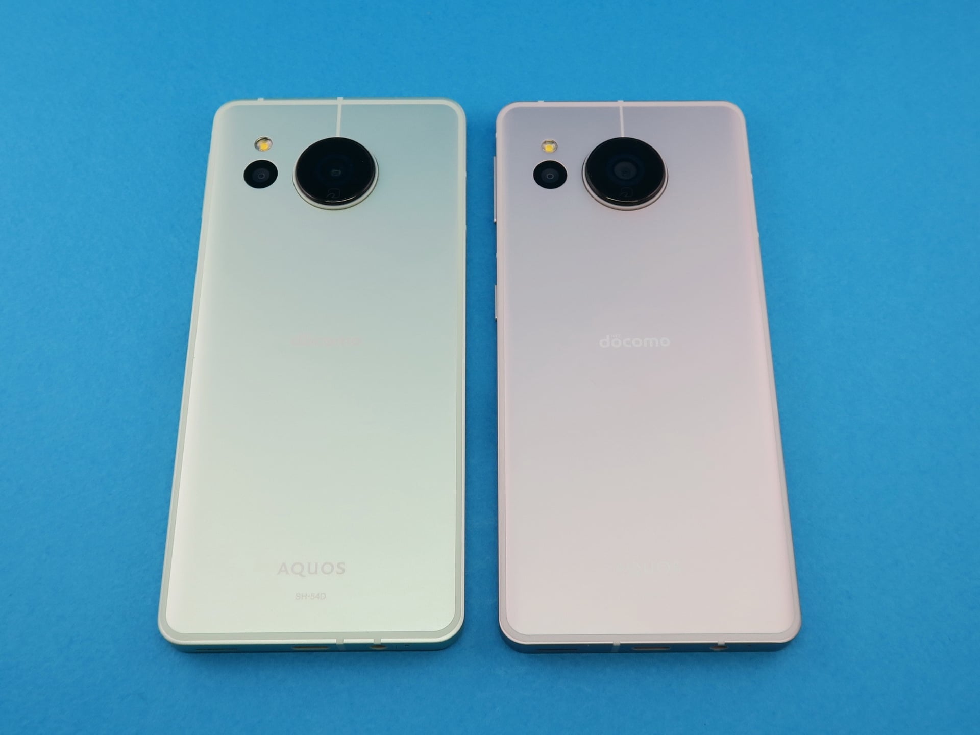 「AQUOS sense8」（左）と「AQUOS sense7」（右）の背面。前面同様、まったく同じ仕上がりで、見分けがつかないが、下部の外部接続端子の横にあるアンテナを内蔵した樹脂パーツの位置が異なる