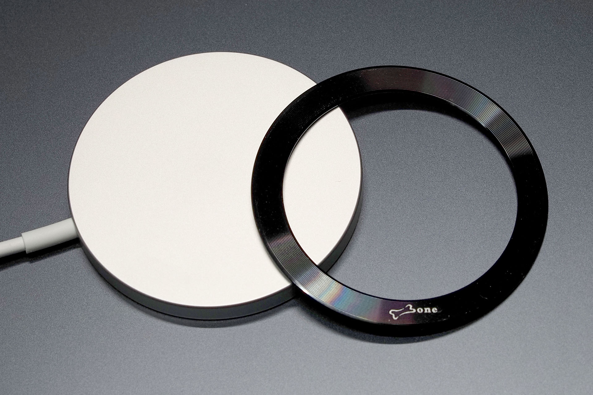 Apple純正MagSafe充電器（の裏面）とスチールリング。このテのスチールリングは裏面に粘着剤が貼ってあり、それでスマートフォンケースなどに貼り付けるタイプ。